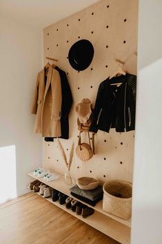 a coat rack with hats and coats hanging on it's sides, along with shoes