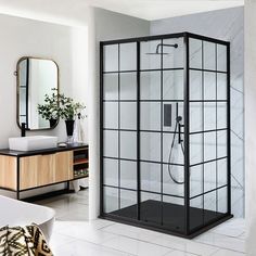 a bathroom with a glass shower stall and white tile flooring, along with a mirror on the wall