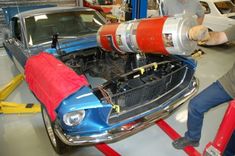 two men working on an old car in a garage