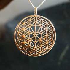 a gold flower of life pendant hanging from a chain