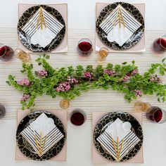 the table is set with black and white plates, silverware, napkins, and flowers