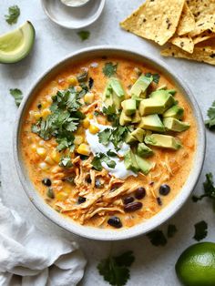 a bowl of chicken tortilla soup with avocado, sour cream and cilantro