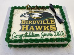 a cake that is sitting on top of a white table with green frosting and the words birdville hawks