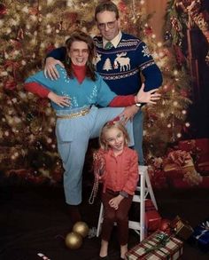 a man and woman pose for a photo in front of a christmas tree