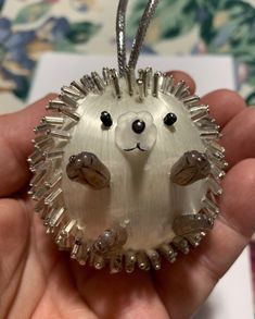 a hand holding a glass ornament shaped like a hedgehog