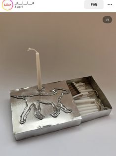 a match box with a lit candle in it and a horse design on the side