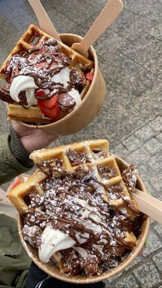 two waffles with chocolate and strawberries in them are being held by someone