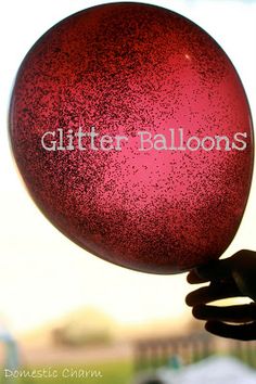 a person holding up a red ball with glitter balloons written on the front and back