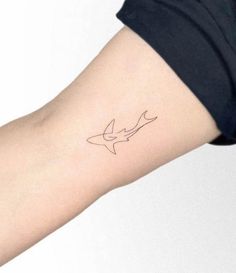 a woman's arm with a small tattoo of a shark on the left side