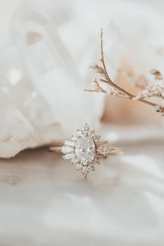 an engagement ring sitting on top of a white piece of cloth next to a flower