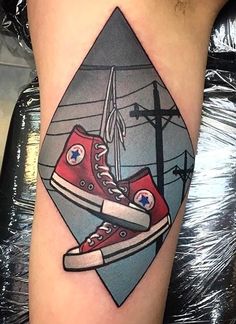 an image of a pair of red sneakers on the thigh with power lines in the background