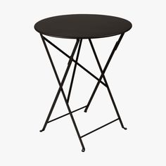 a small black table with metal legs and a round top on an isolated white background