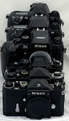 a bunch of cameras stacked on top of each other in front of a white background