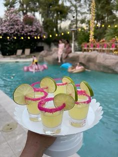 a person holding a tray with drinks near a swimming pool