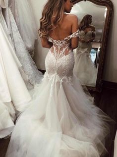 a woman in a wedding dress looking at herself in the mirror