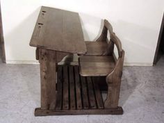 an old wooden table and chair sitting next to each other on the floor in front of a white wall