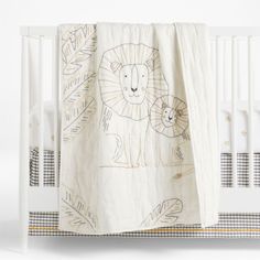 a white crib bed with a lion blanket on it's side and an animal drawn on the sheet