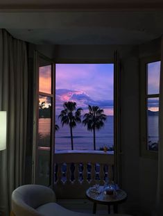 a room with two chairs and a table in front of a window overlooking the ocean