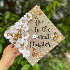 someone holding up a graduation cap that says on to the next charter with butterflies around it