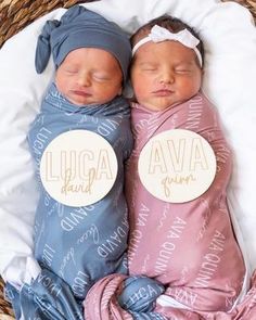 two newborn babies wrapped in blankets and sleeping on a wicker basket with name tags