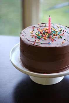 a chocolate cake with sprinkles and a single candle