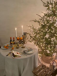 a christmas tree is lit up in the corner of a room next to a dining table