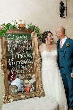 a bride and groom standing in front of a chalkboard sign for their wedding day