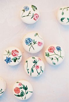 six decorated eggs sitting on top of a white table covered in floral designs and leaves