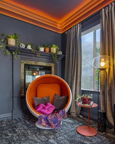 an orange chair sitting in front of a window with potted plants on top of it