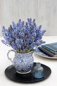 a blue and white vase filled with purple flowers on top of a black platter