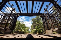 an open metal structure with lots of trees in the background and blue sky above it