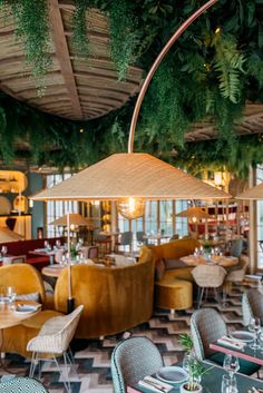 the interior of a restaurant with tables, chairs and umbrellas hanging from the ceiling