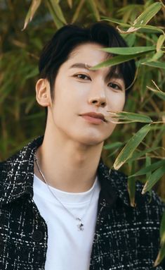 a young man standing in front of some leaves