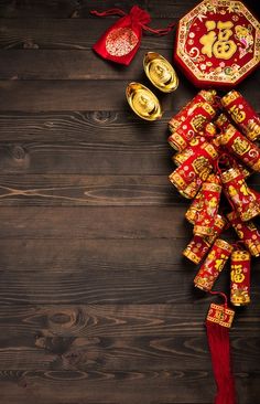 a red and gold decoration on a wooden surface with other items around it, including two bells