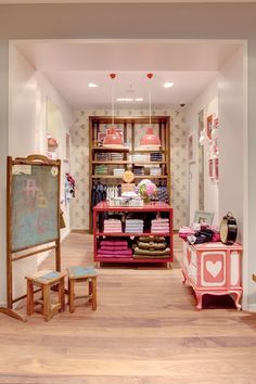 the inside of a clothing store with pink furniture and pictures on the wall behind it