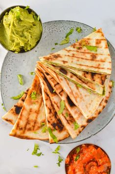 several quesadillas on a plate with guacamole and salsa