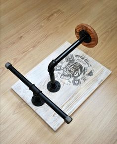 two black iron pipe holders sitting on top of a piece of paper with a wooden stand