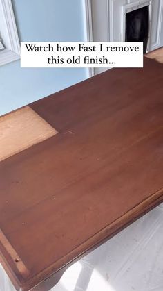 a wooden table with a sign that says watch how fast i remove this old finish