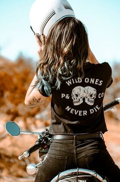 a woman on a motorcycle wearing a t - shirt that says wild ones never die