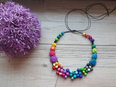 a necklace made out of colorful beads on a table next to a purple flower and headband