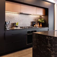 a kitchen with marble counter tops and black cabinets