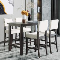 a dining room table with four chairs and a vase filled with flowers