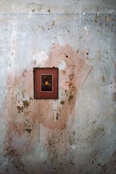 an old wall with a small square hole in the middle and a man's face on it