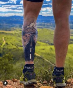 a man's legs with tattoos on the side of his leg, and an image of a road going through them