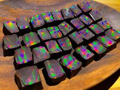 a wooden table topped with lots of black and green pieces of chocolate covered in iridescents