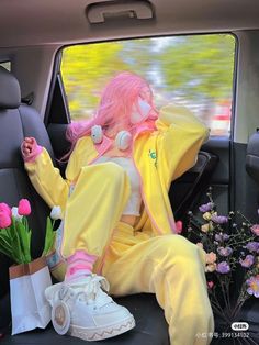 a pink haired woman sitting in the back seat of a car with headphones on