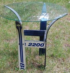 a glass table sitting on top of a grass covered field next to a blue chair