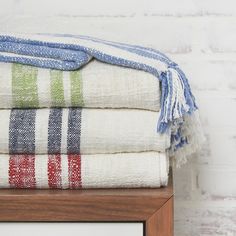 a stack of towels sitting on top of a wooden shelf next to a white brick wall