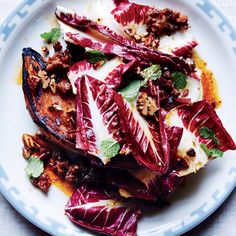 a white plate topped with meat and veggies on top of a blue and white table cloth