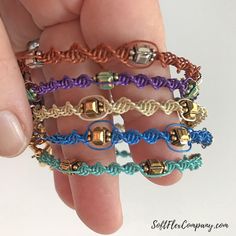 a hand holding four different colored bracelets